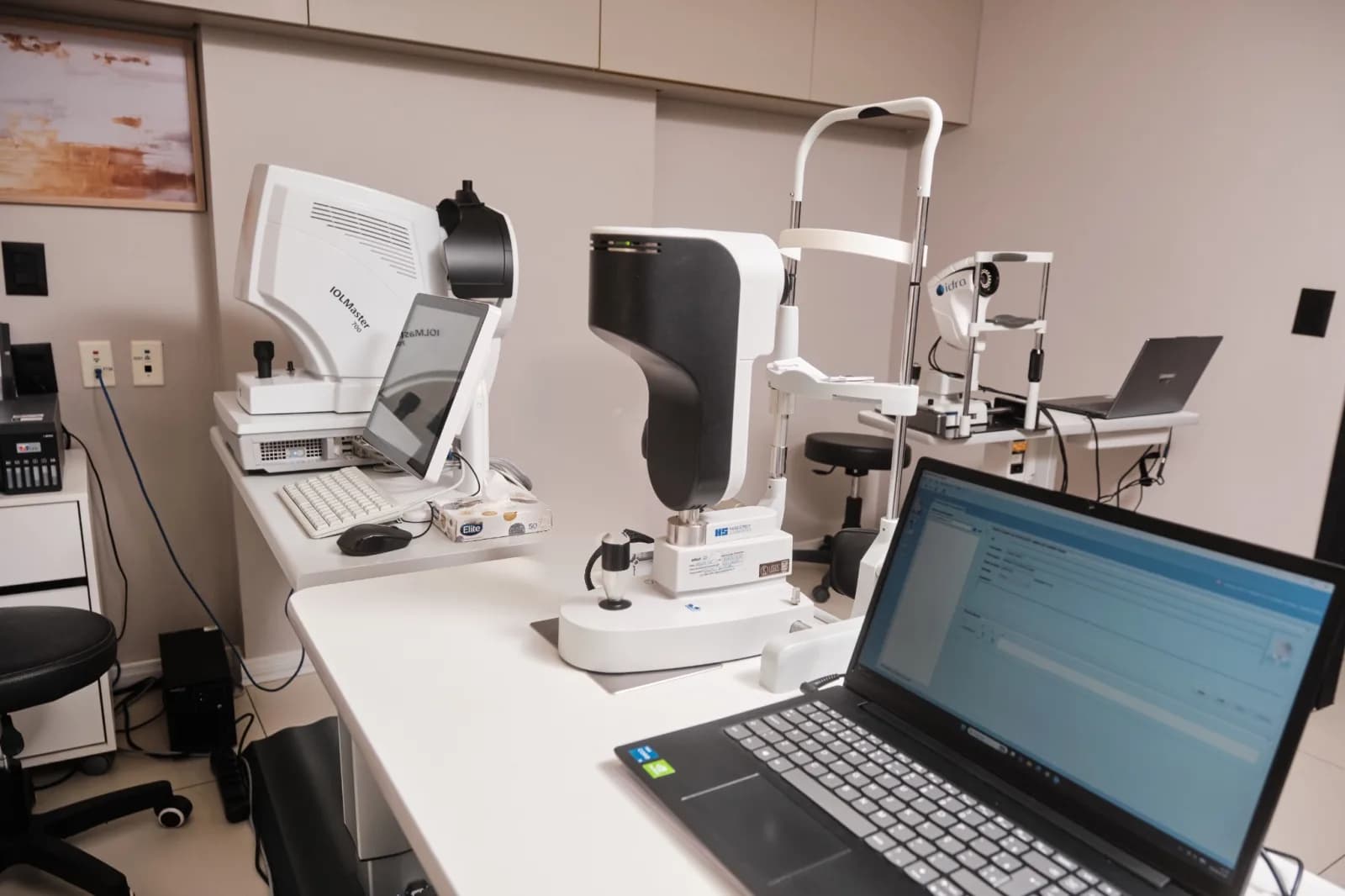 Bancada de diagnóstico da Logos Vision com o biômetro IOLMaster 700, usado no cálculo da lente intraocular, a lâmpada de fenda e um notebook com o sistema de laudos