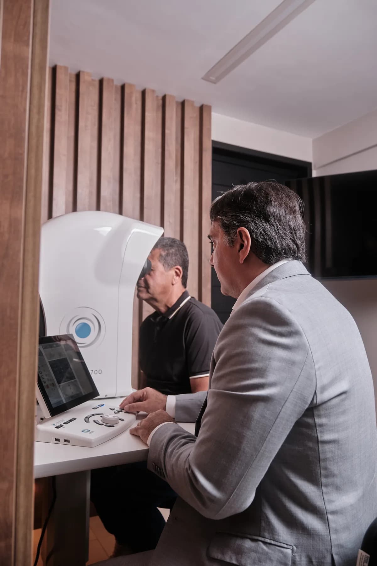 Dr. João Marcelo Lyra acompanhando no computador o exame de um paciente posicionado no equipamento de diagnóstico