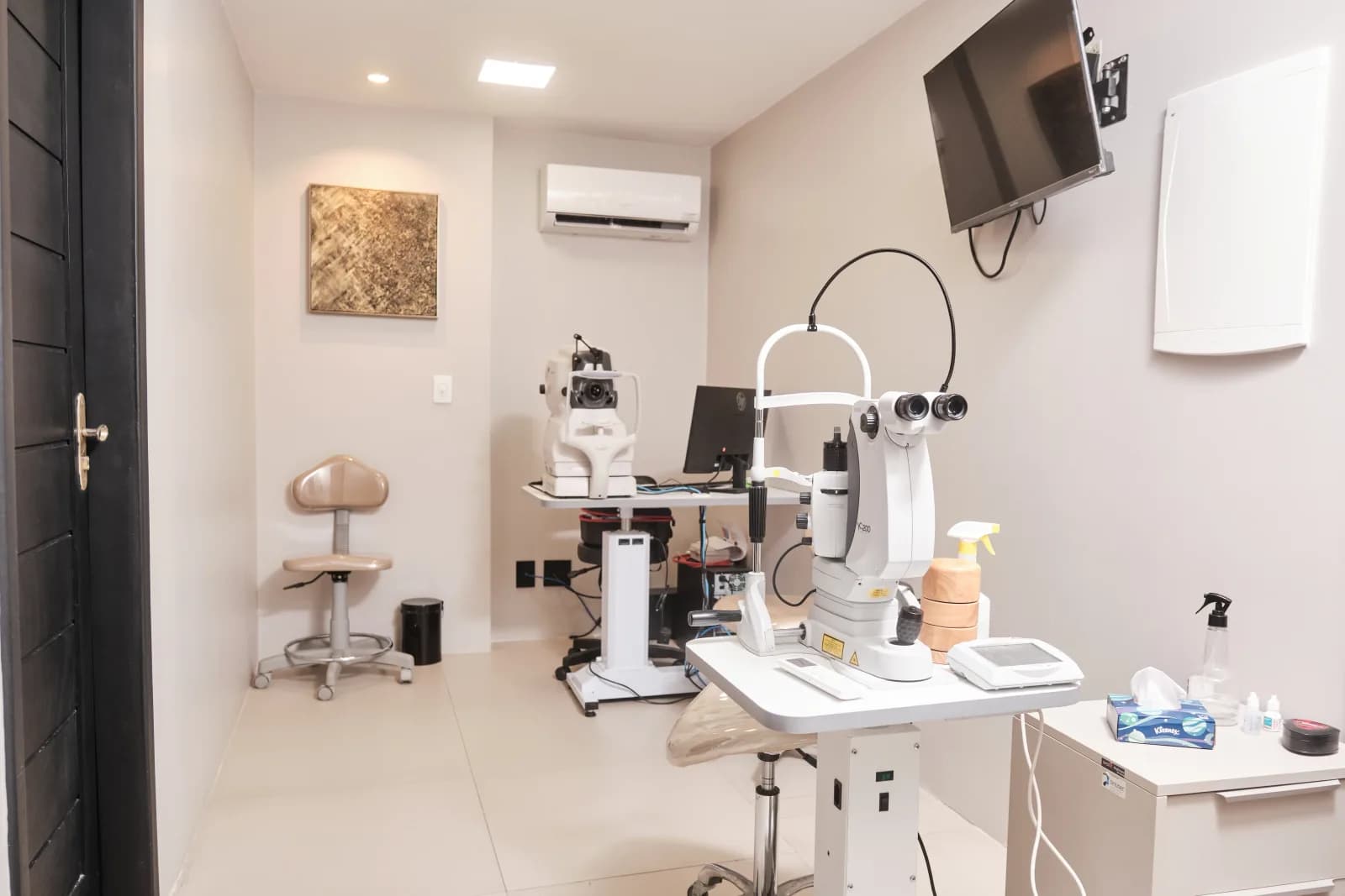 Sala de exames da Logos Vision, com lâmpada de fenda, retinógrafo e monitor de laudos